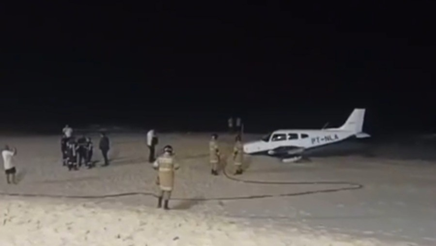 Foto reprodução de um vídeo mostra o avião parado na areia com bombeiros ao redor